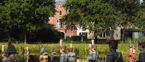 Una rievocazione storica con figure in costumi d'epoca vicino all'acqua, con un edificio sullo sfondo.