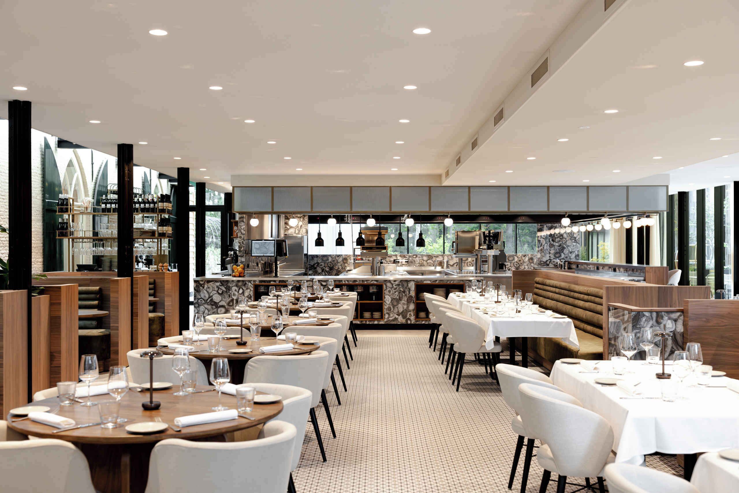 Un restaurant doté de plusieurs tables, de chaises et d’un espace cuisine.