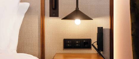 A neatly made hotel room with a bed, a bedside table with a lamp, and a small wooden cabinet.