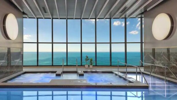Piscina interior con vistas al océano a través de amplios ventanales.