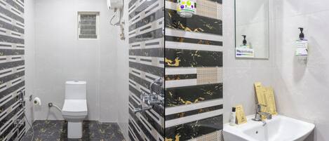 A bathroom with a toilet, shower, and sink.
