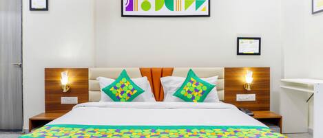 A hotel room with a large bed, two nightstands, a wooden headboard, and a colorful abstract painting on the wall.