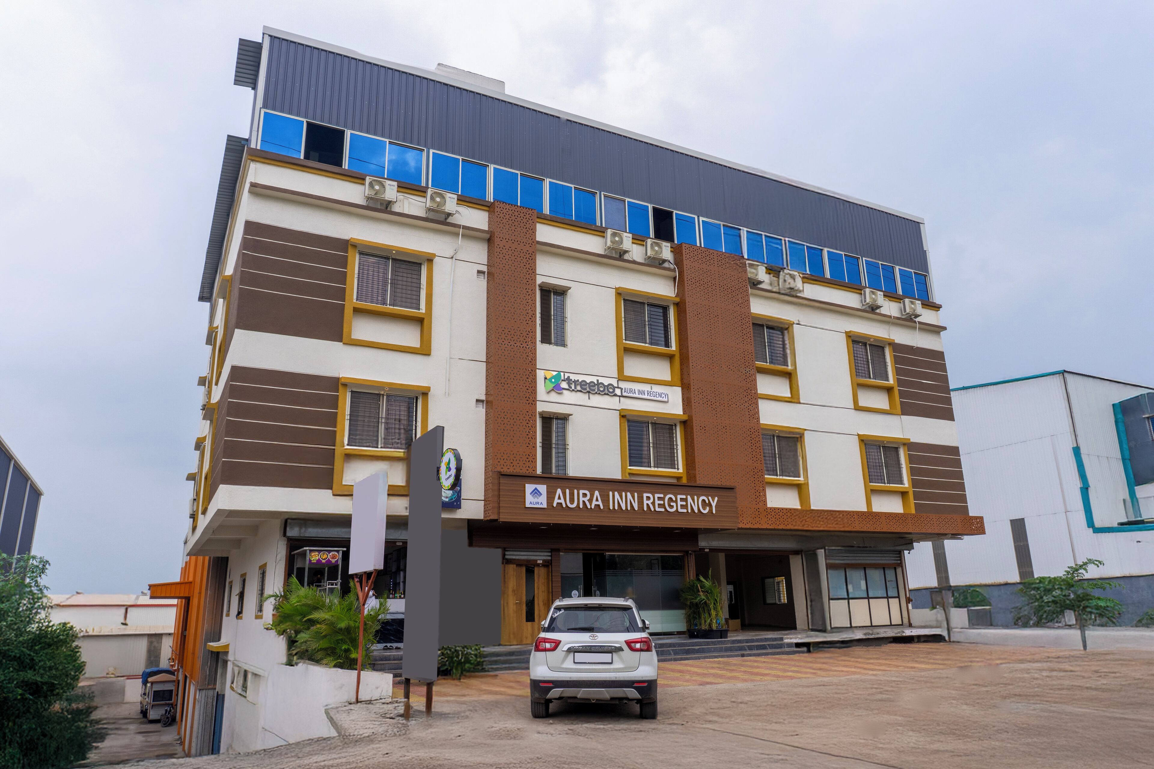 Un hotel de varios pisos con un letrero que dice 'AURA INN REGENCY'.