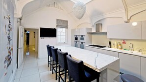 Een moderne keuken met een marmeren aanrecht, barstoelen en een hangende lamp.