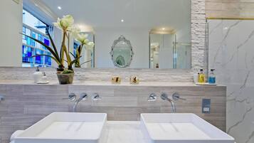 Un baño moderno con dos lavamanos, un espejo grande y una planta en maceta.