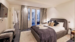 Een moderne hotelkamer met een groot bed, een flatscreen televisie en een glazen schuifdeur naar een balkon.