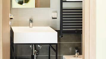Un baño moderno con un lavamanos blanco, un espejo, un perchero para toallas y una bañera.