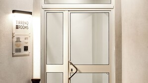 A double door with a glass panel, a sign for 'Tirreno Rooms', and a floor lamp. - CODE ROOMS by Hotel Villa Tirreno (Tarquinia)