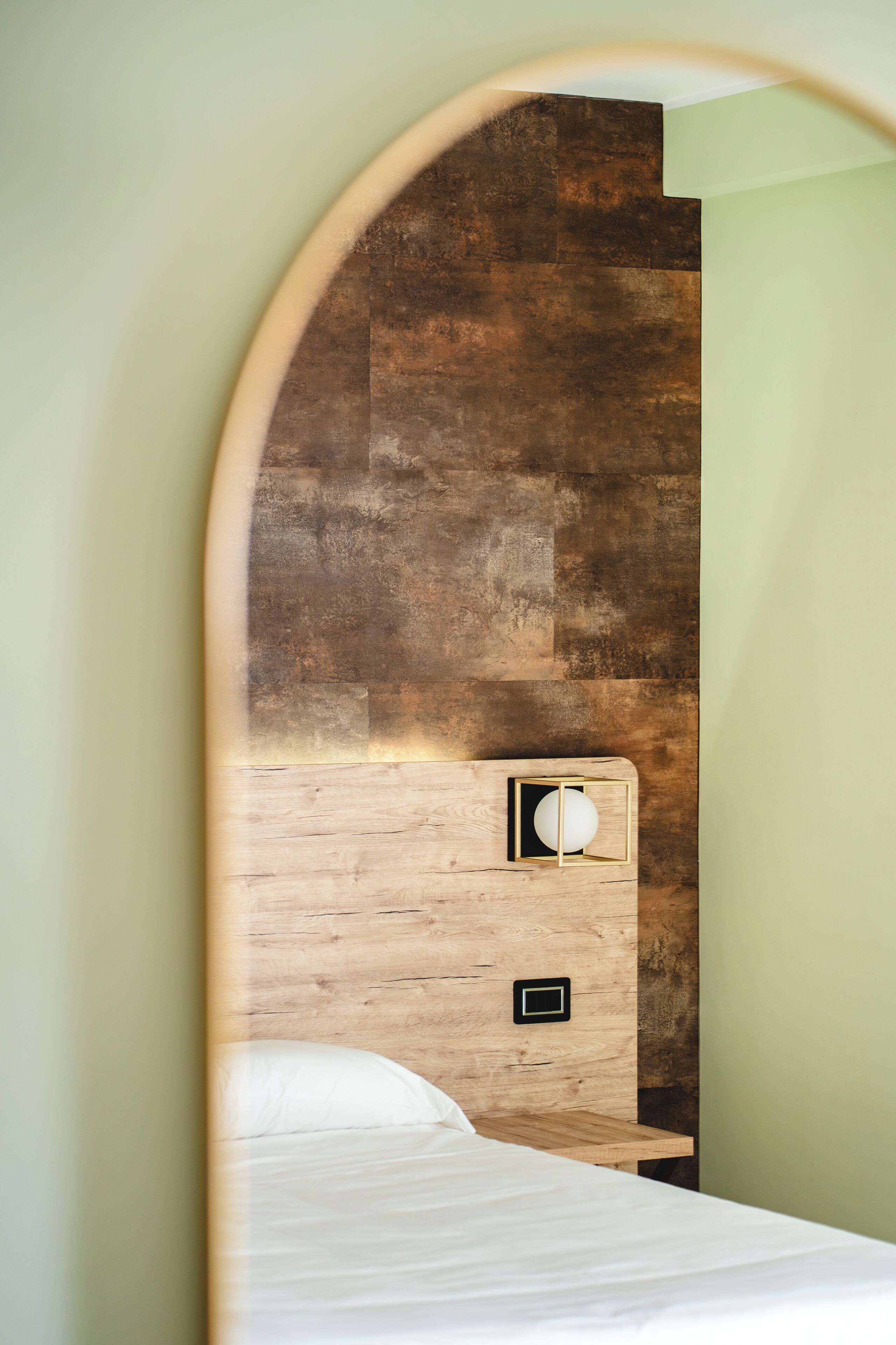 Un dormitorio con cabecera de madera, una mesita de noche con lámpara y cama con ropa blanca.