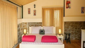 Une chambre à coucher avec un lit, deux lampes de chevet, une radio et un mur en pierre.