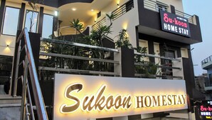 A modern building with a sign that reads "Sukoon Homestay." - Sukoon Homestay: Peaceful stay, tasty food, comfort in nature. (Agra)