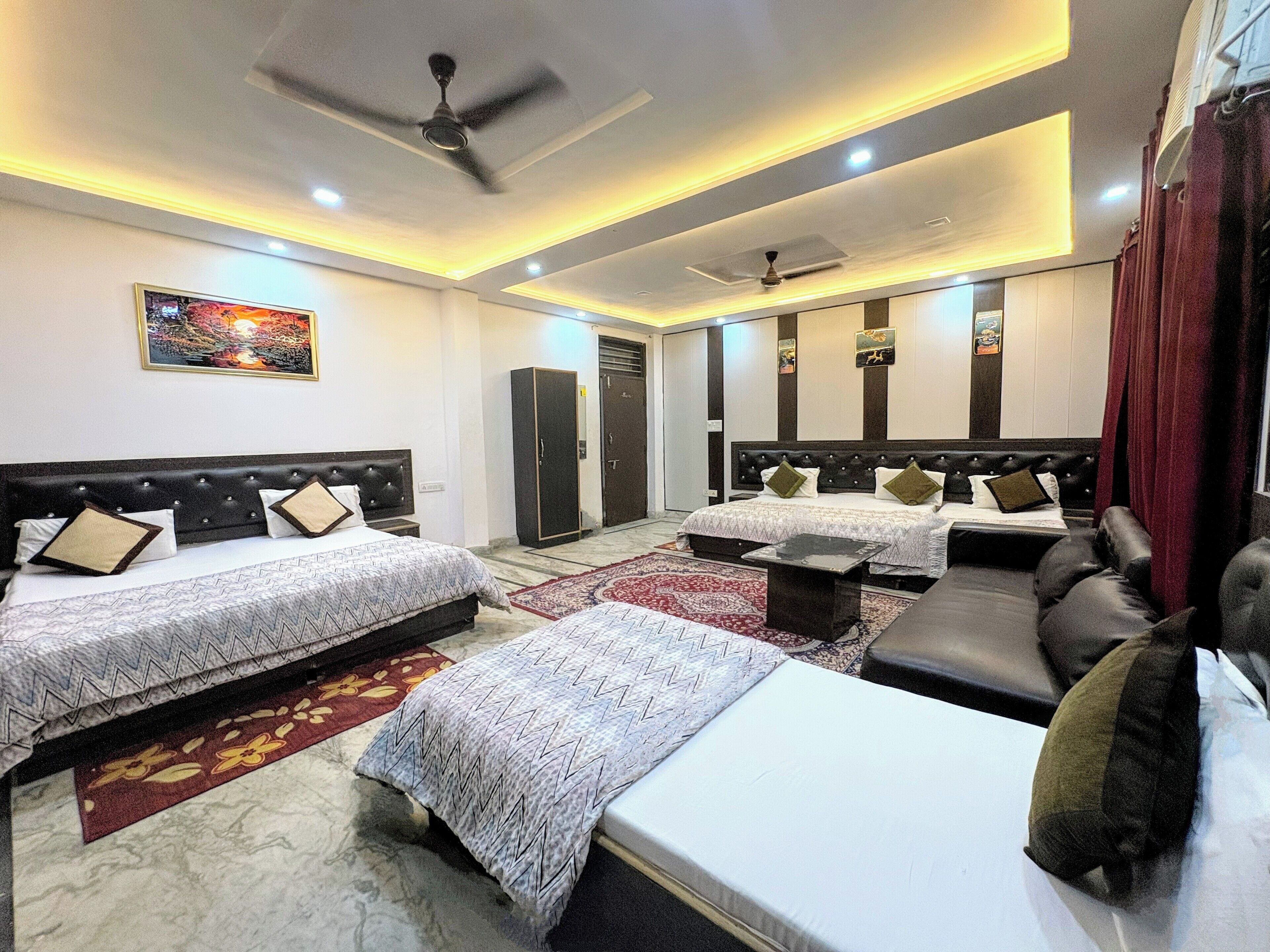 A hotel room with two beds, a sofa, a ceiling fan, and a large mirror.
