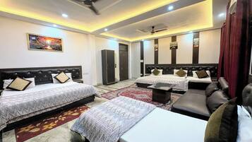 A hotel room with two beds, a sofa, a ceiling fan, and a large mirror.