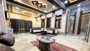A spacious lounge area with a central coffee table, sofas, and patterned rugs. - Sukoon Homestay: Peaceful stay, tasty food, comfort in nature. (Agra)