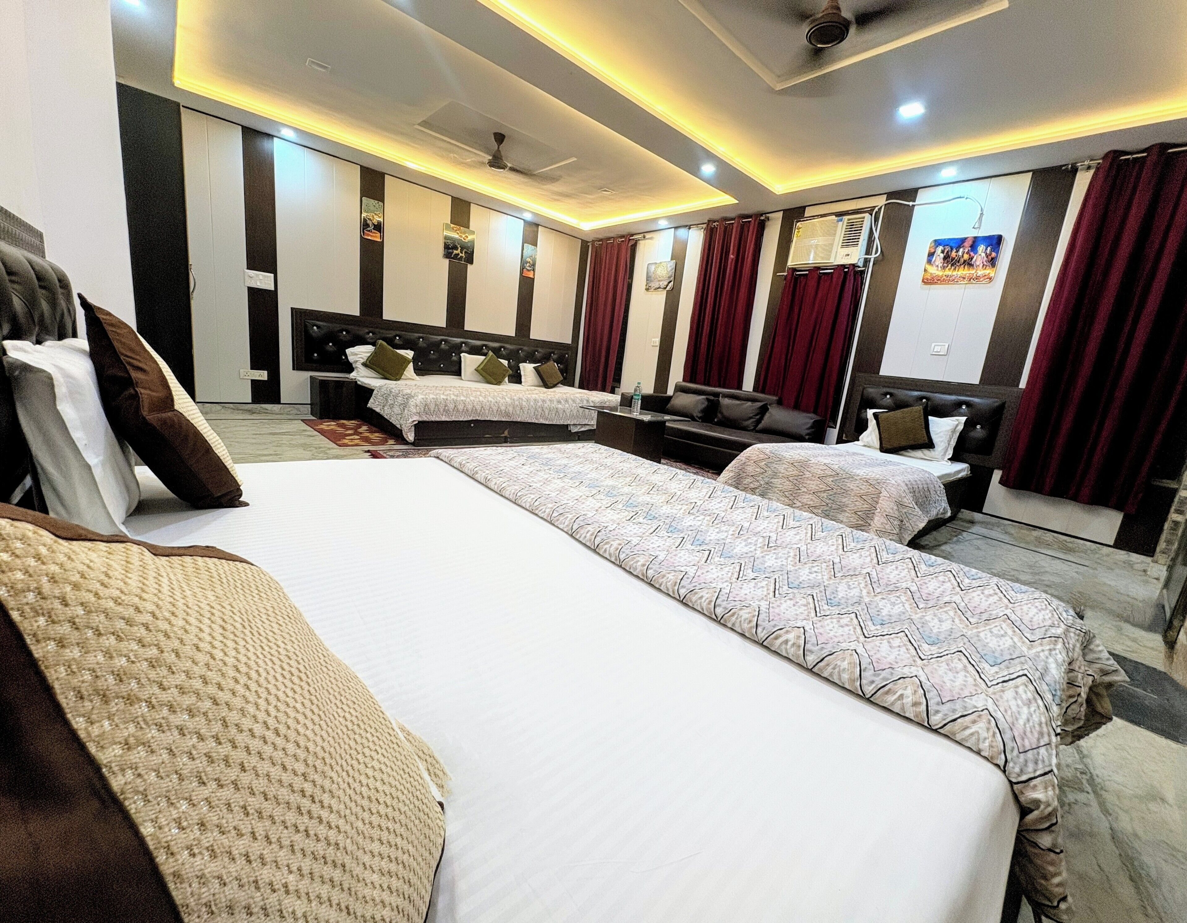 A hotel room with two beds, a sofa, a TV, and a ceiling fan.