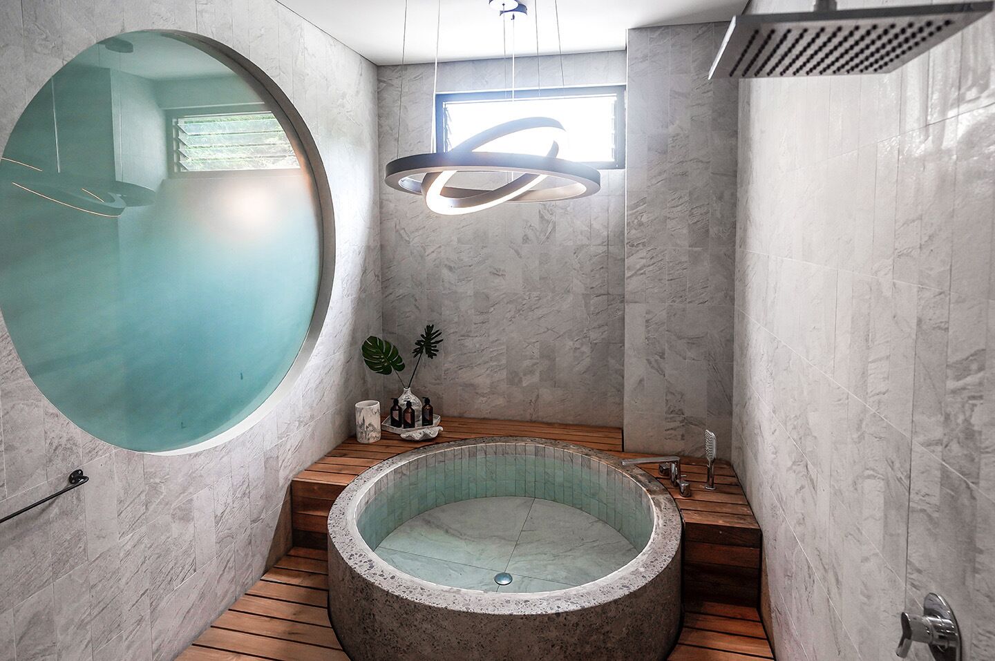 Un baño moderno con una bañera de hidromasaje circular, un espejo grande y un tragaluz.