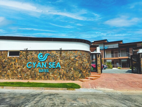 Un hotel llamado "Cyan Sea Suites" con fachada de piedra y diseño moderno.