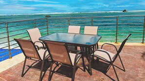 Une table et des chaises sur une terrasse avec vue sur l’océan.