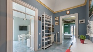 A room with a white table, red chairs, a white shelving unit, and a potted plant. - Casa Garibaldi in Piazza by Wonderful Italy (Palermo)