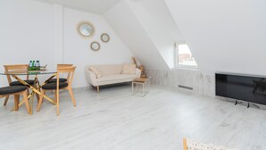 Una sala de estar moderna con una mesa de comedor de vidrio, un sofá color beige y un televisor de pantalla plana.