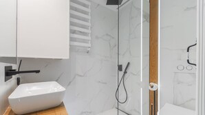 Un baño moderno con lavamanos, ducha e inodoro blancos.