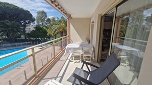 A balcony with a pool view, a table with chairs, and a chair. - STUDIO + SLEEPING AREA CLOSE TO SHOPS AND BEACHES (Sainte-Maxime)