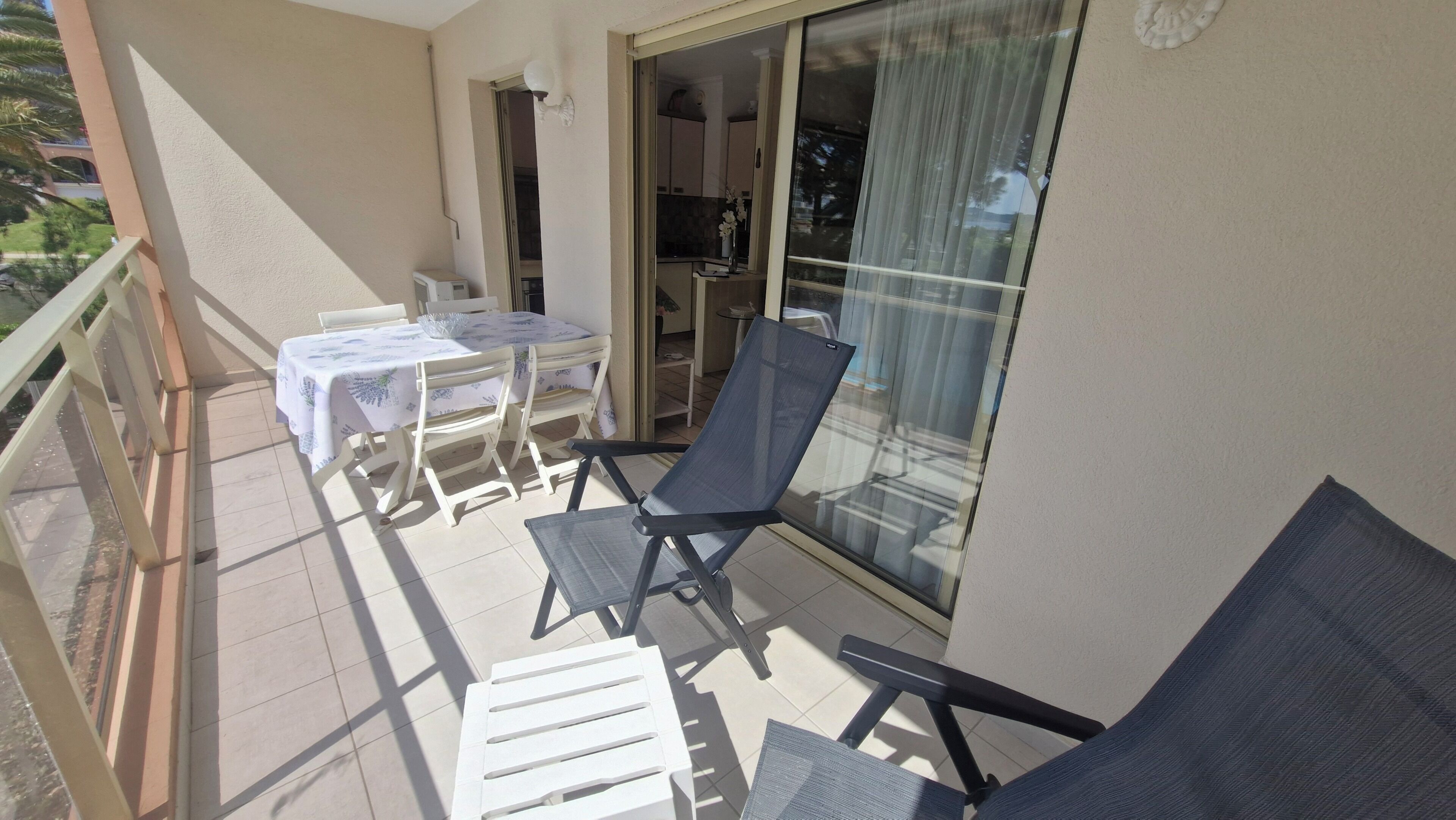 Ein Balkon mit Tisch und Stühlen, eine Glastür und Blick ins Innere.