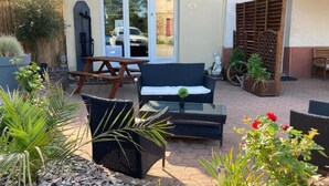 Un espace extérieur aménagé en terrasse, avec des meubles en osier, une table et des plantes en pot.