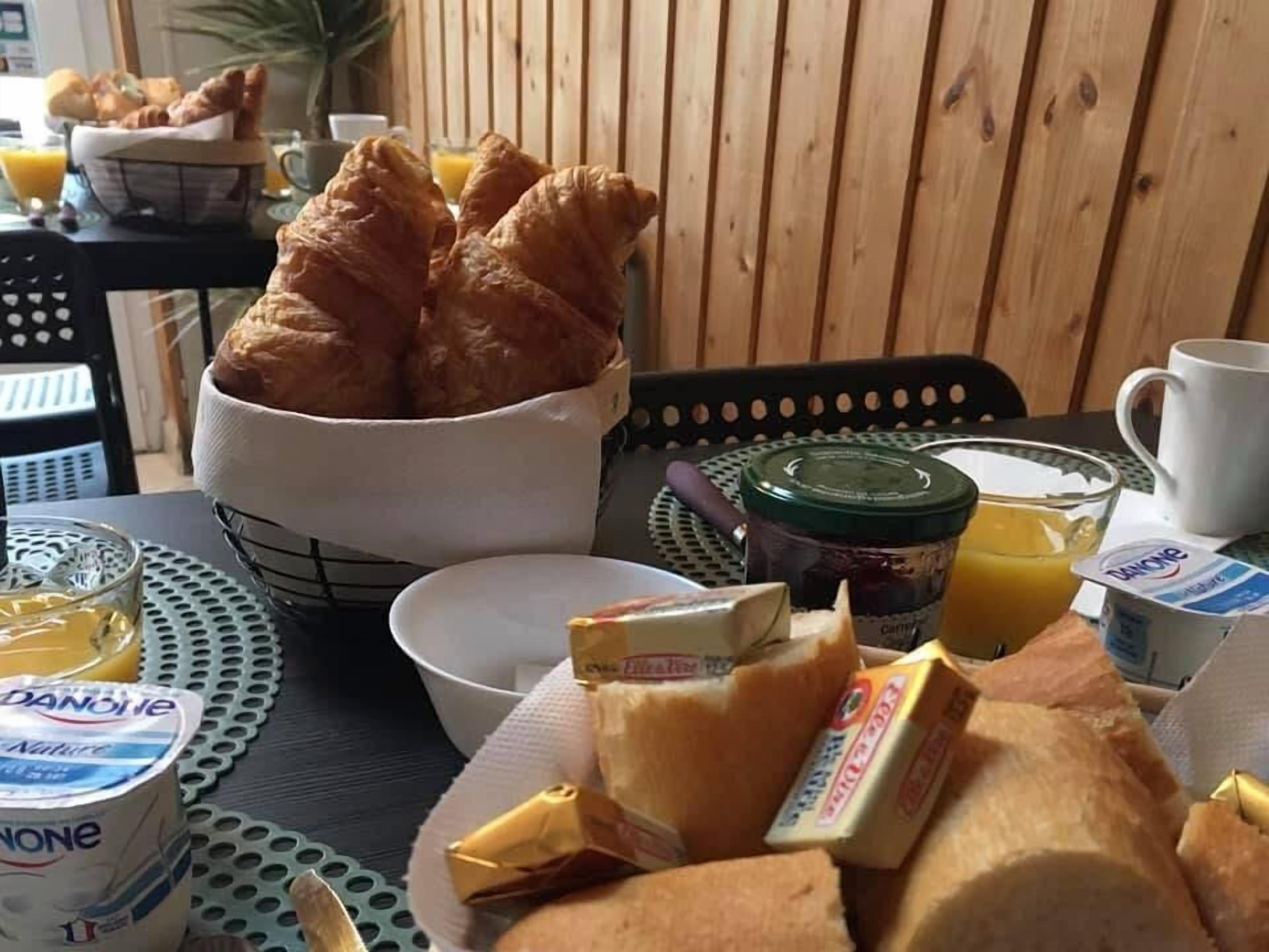 A breakfast table with croissants, orange juice, and Danone yogurt.