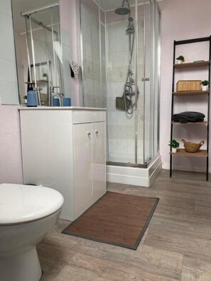 A modern bathroom with a glass shower enclosure, a white toilet, and a wooden floor. - Chambres d hotes à la ferme  (Forest-Montiers)