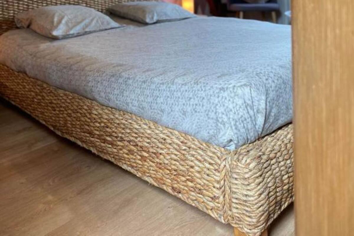Una habitación con una cama, un muro con estampado geométrico y una estructura de techo de madera.