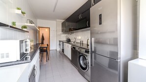 Una cocina moderna con electrodomésticos de acero inoxidable, lavadora y un comedor con mesa y sillas.