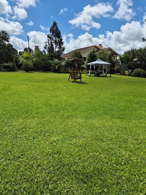 A well-maintained grassy lawn with a swing set and a gazebo in the background. - A farmhouse on the Tea farm estate (Kiambu County)