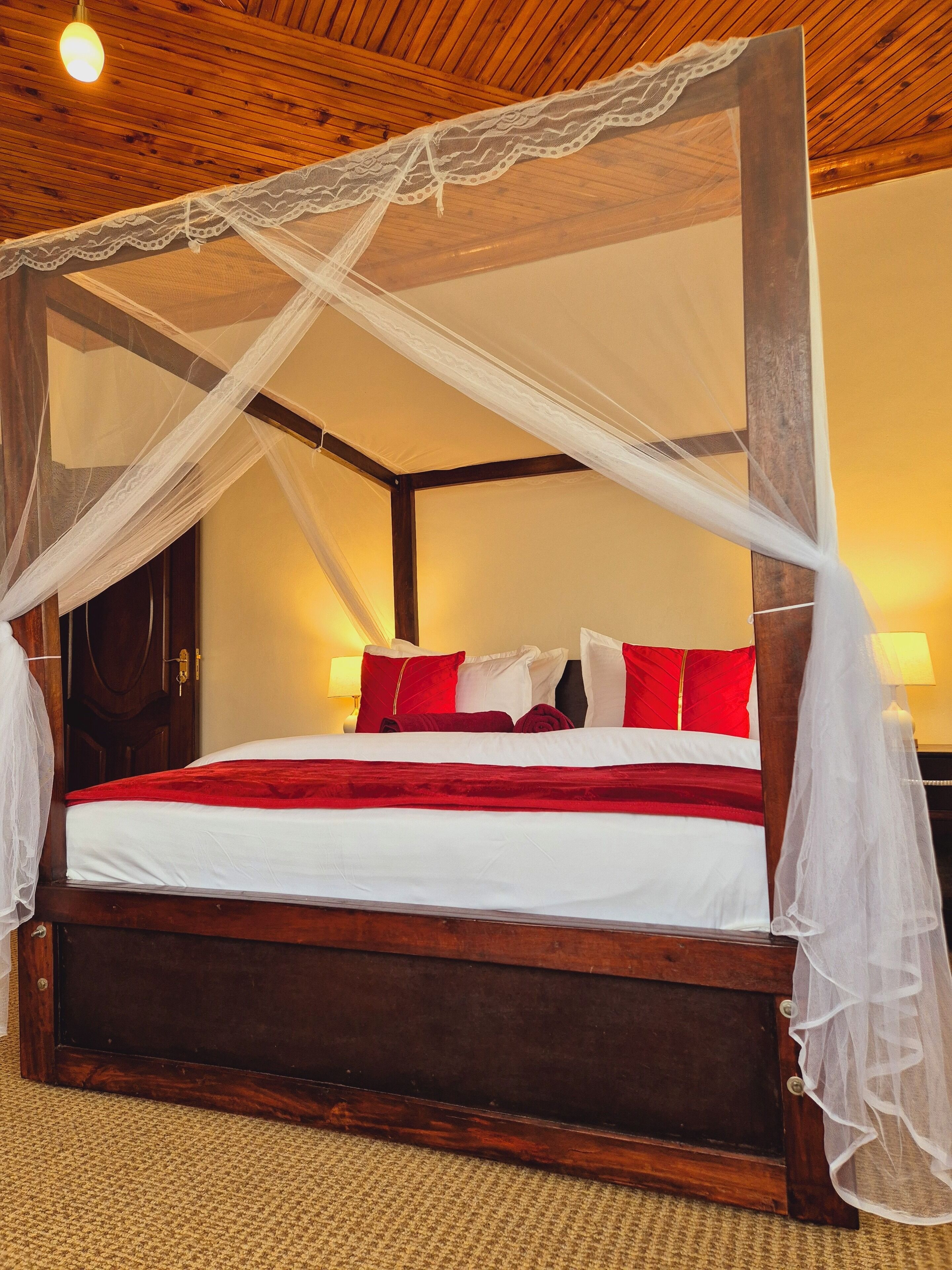 A four-poster bed with a white canopy, red and white pillows, and a wooden headboard.