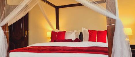A four-poster bed with a white canopy, red and white pillows, and a wooden headboard.