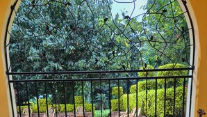 A room with a large arched window overlooking a garden. There is a wooden table with a vase of flowers in the center. - A  farmhouse on the Tea farm estate (Kiambu County)