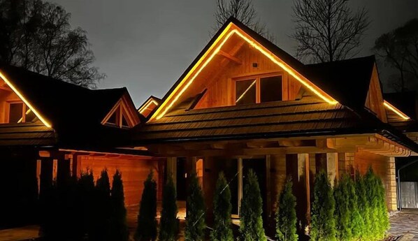 Cozy cabin-style building with a triangular roof, surrounded by a beautifully maintained garden.