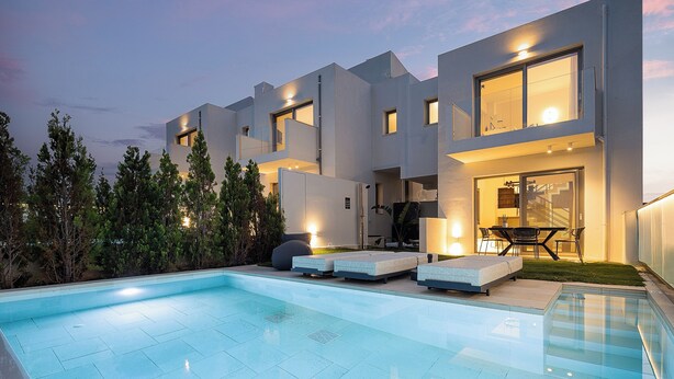Ein modernes Haus mit Swimmingpool, Sitzgelegenheiten im Freien und einer Terrassenfläche.