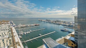 Een jachthaven met aangemeerde boten, een groot schip en een gebouw met een modern ontwerp.