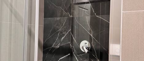 Eine moderne Dusche mit Glastür und Marmoroptik.