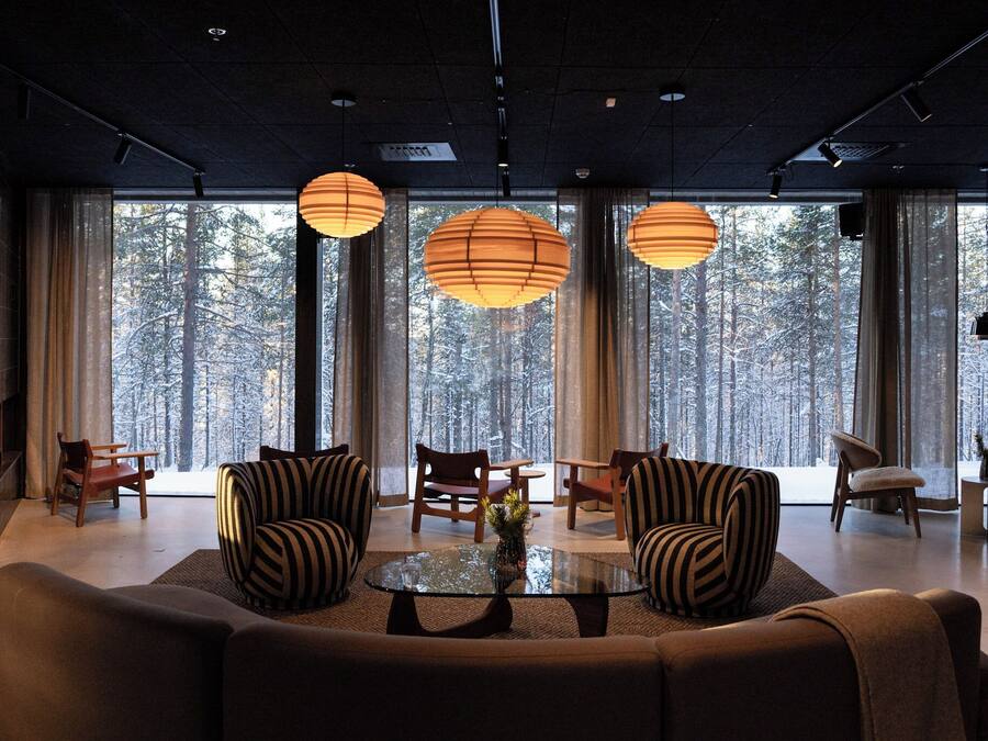 A modern living room with a large window, a fireplace, and striped armchairs.