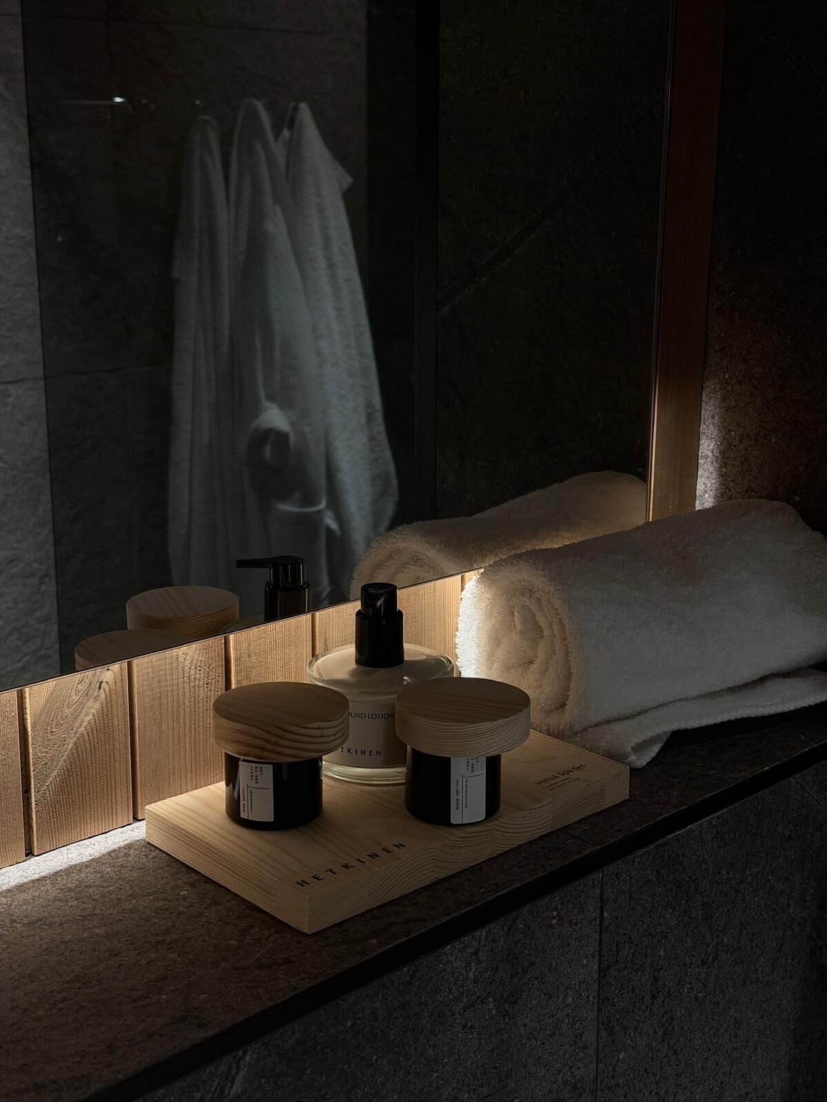 A bathroom with a wooden vanity, a mirror, and a towel hanging on a rack.