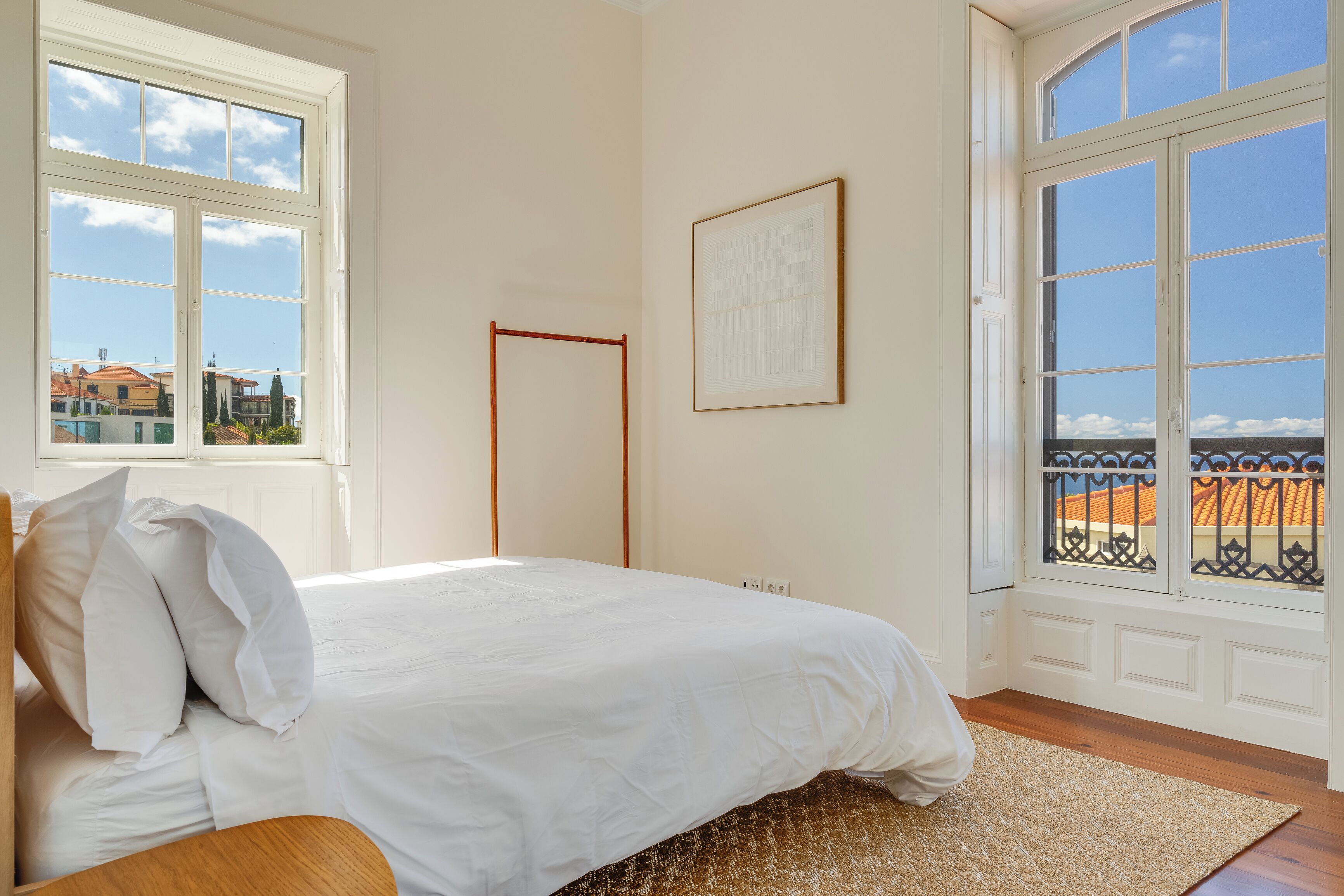 Ein Schlafzimmer mit Bett, Fenster und Blick auf Gebäude.