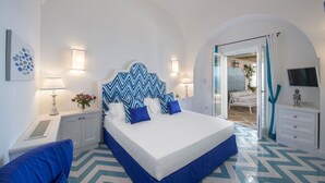 Un dormitorio con cama, mesitas de noche, lámpara y televisor.