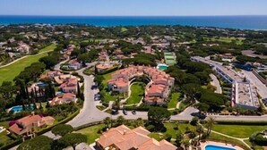 An aerial view of a residential area with houses, roads, and a large body of water in the background. - 2 bed renovated apartment in vale do lobo Algarve (Loulé)