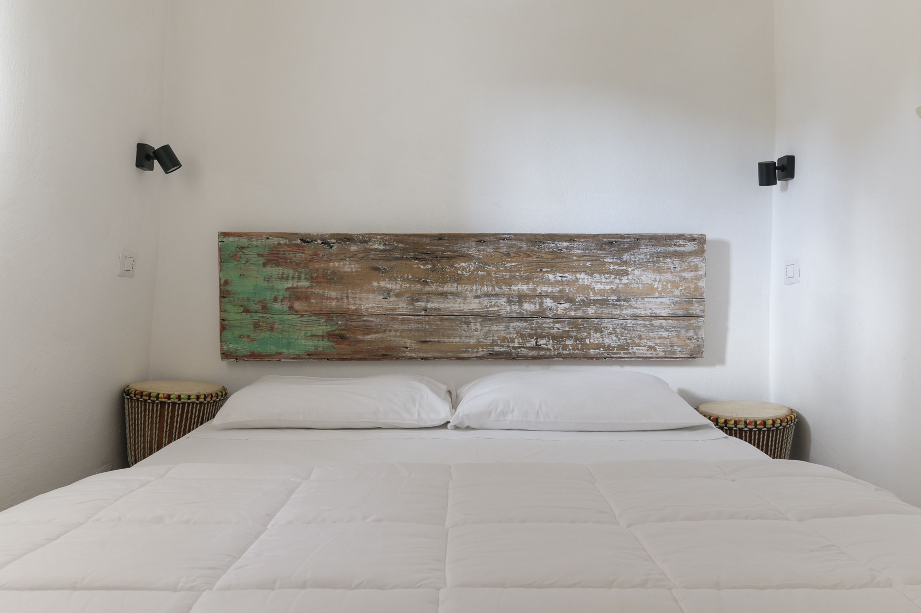 A bedroom with a large bed, two bedside tables, and a rustic wooden headboard.
