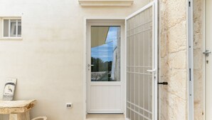 A white door with a glass panel, a small window, and a stone wall. - Dimora Upupa by Wonderful Italy (Ostuni)