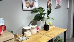 Une table en bois avec des ustensiles de cuisine, une plante en pot et des œuvres d’art murales.