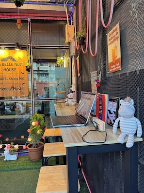 Une auberge de jeunesse chaleureuse, avec une enseigne en bois, un ordinateur portable posé sur une table, un jouet en peluche et une petite plante en pot.