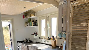 A modern kitchen with wooden cabinets, a large sink, and a countertop with various kitchen items. - Beach house on the North Sea coast - IJmuiden Kleine Strand (IJmuiden)